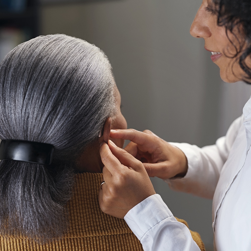 Femme de 45 ans en consultation chez un audioprothésiste dans le but de se faire fabriquer des bouchons d'oreille moulés sur mesure