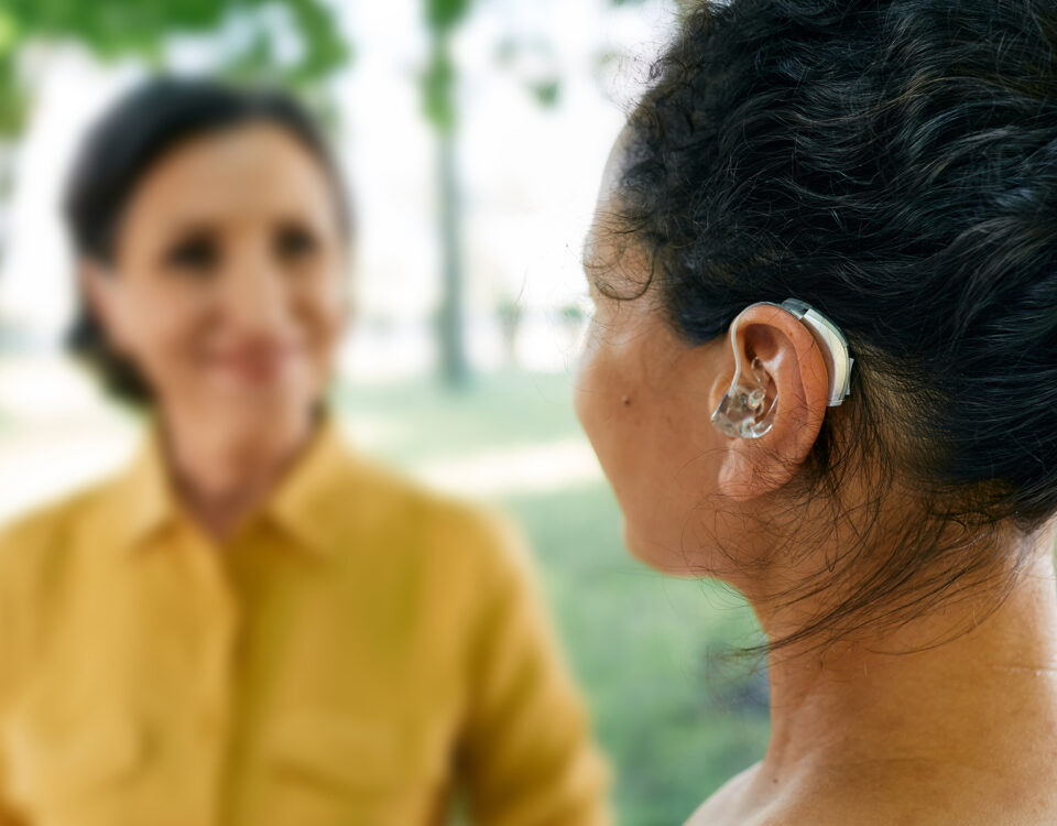 Zoom sur une prothèse auditive contour d'oreille portée par une jeune femme
